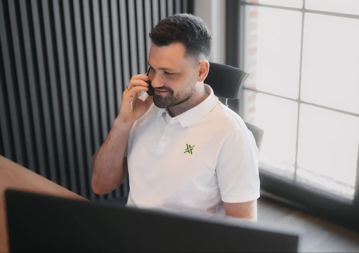 Büroangestellter am Schreibtisch im Telefonat mit Kunden